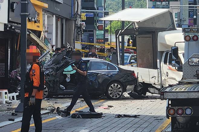 12일 오후 부산 해운대구 한 도로에서 벤츠 승용차가 인도로 돌진해 정차해있던 트럭과 보행자 2명을 치고 한 점포를 충격한 뒤 멈춰 서 있다. [연합]