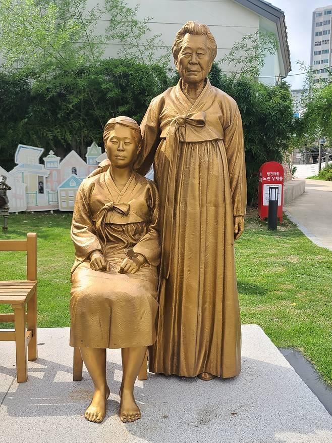 21세기 강한 나라 만들기에 기여한 할머니가 어린시절 참 많이 아팠던 자신의 모습을 다독이는 느낌의 양림동 소녀상