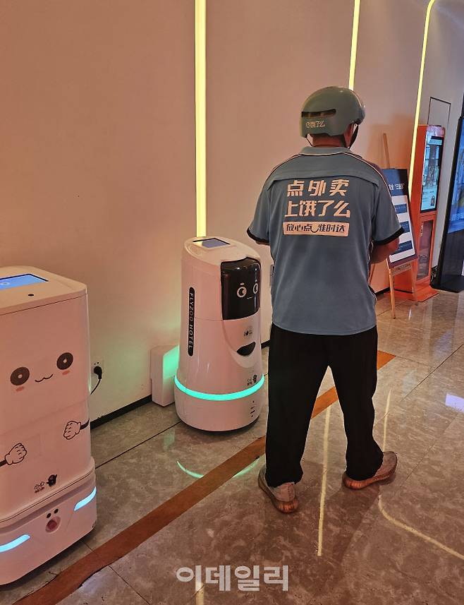 중국 항저우에 있는 알리바바 플라이주(FlyZoo)호텔 로비에 있는 로봇에 배달원이 물품을 넣으려 하고 있다. (사진=경계영 기자)