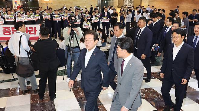 국민의힘 의원들이 야당을 규탄하는 가운데 국회 본회의장으로 들어가는 더불어민주당 이재명 대표를 비롯한 의원들