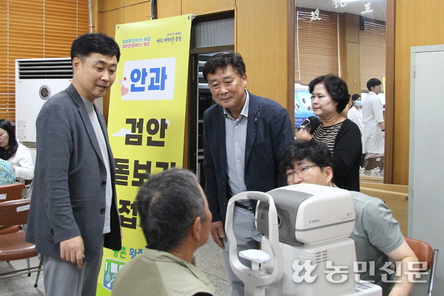 김형수 NH농협 안성시지부장(서있는 사람 왼쪽부터)과 김윤배 양성농협 조합장이 안과 검진을 받은 어르신을 살펴보고 있다.