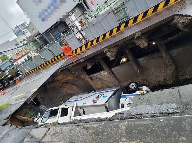 21일 오전 부산 사상구 한 도로에서 가로 10m, 세로 5m, 깊이 8m 가량의 대형 땅꺼짐 현상(싱크홀)이 발생해 도로에서 배수 지원을 하던 삼락119안전센터 배수 차량과 5톤 트럭이 빠져있다. /뉴스1