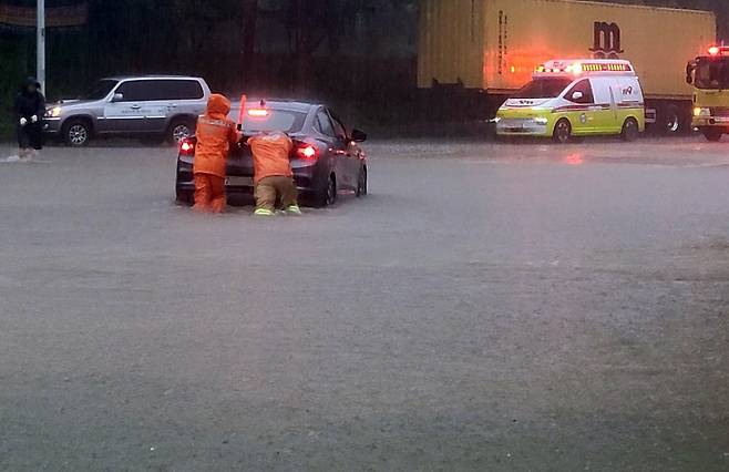 Firefighters assist in moving a vehicle isolated by floodwaters on a submerged road in Dunsan-ri, Bongdong-eup, Wanju County, North Jeolla Province, on the morning of Sept. 21, 2024./Yonhap News