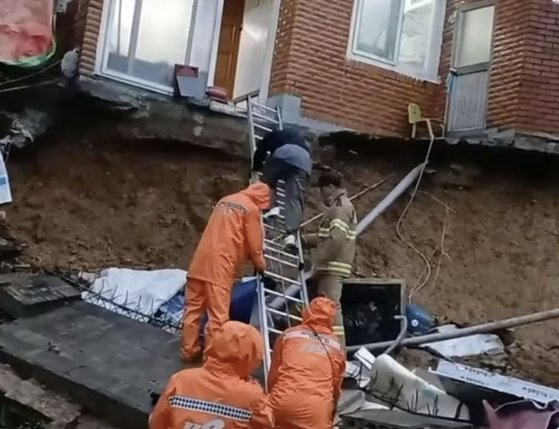 지난 21일 부산시 부산진구 연지동의 한 주택 담벼락 등이 무너지면서 2명이 집 안에 고립돼 소방대원이 구조하고 있다. 사진 부산소방재난본부