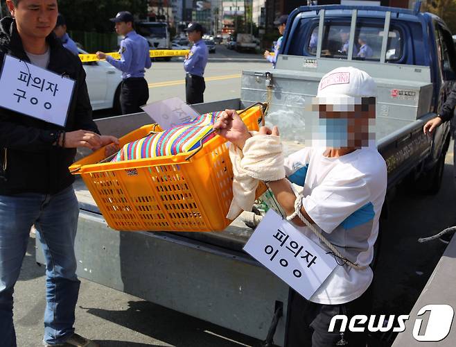 부산항 제2부두에서 이불에 싸인 채 시신이 떠오른 사건과 관련해 3일 오전 부산 남구 문현동 범일교에서 살해 피의자 공범 이모씨(45)가 범행 당시 피해자 김모씨(56·여)의 시신을 노란 바구니에 담아 다리 밑으로 던지는 장면을 재연하고 있다.(부산해양경찰서 제공) ⓒ News1