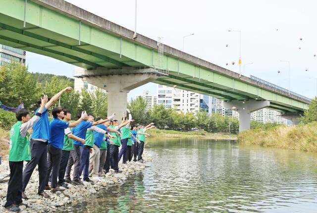 지난 26일 경남 창원시 광려천에서 하이트진로 임직원과 지역 관계자들이 환경정화활동에 참여하고 있다. /하이트진로