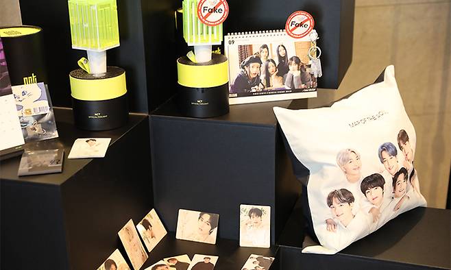 특허청 주최로 26일 서울 서초구 JW메리어트호텔에서 열린 ‘민·관 협력 위조상품 대응강화 콘퍼런스’에서 뉴진스 공식 달력과 NCT 공식팬라이트 등에 짝퉁 스티커가 붙여져있다. 특허청 제공