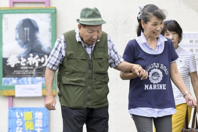 강제 자백 등으로 살인 유죄 판결을 받은 후 거의 60년 동안 사형수 생활을 해온 88세의 전직 복서 이와오 하카마다(왼쪽)가 25일 일본 시즈오카현 하마마쓰에서 지지자의 도움을 받으며 산책을 하고 있다. 시즈오카=AP 뉴시스