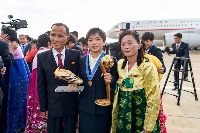 북한의 최일선(가운데)이 28일 귀국해 평양국제공항에서 2024년 국제축구연맹(FIFA) U-20 여자 월드컵 트로피를 손에 쥔 채 기념사진을 찍고 있다. 평양/AFP 연합뉴스