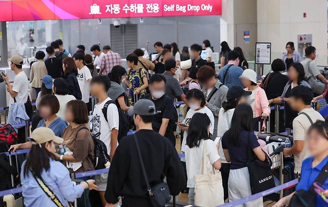 People stand in line behind a check-in counter at Incheon International Airport, Terminal 1 on Sept. 13. (Yonhap)