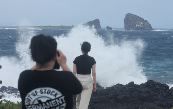 People take photos near the ocean in Seogwipo, Jeju Island, as large waves crash ahead of Typhoon Jongdari's approach on Aug. 20. [YONHAP]