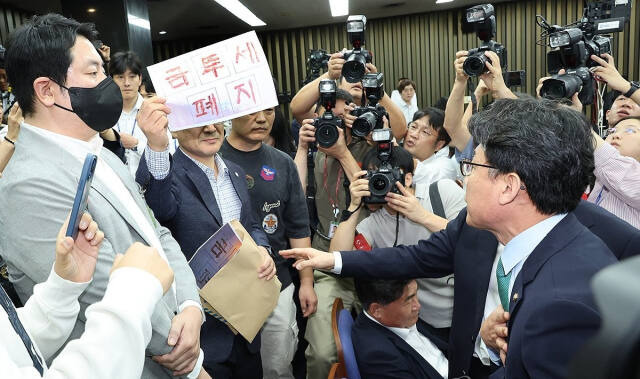 지난 24일 오전 서울 여의도 국회에서 '행복하고 정의로운 대한민국, 금융투자소득세 시행은 어떻게?'라는 주제로 열린 더불어민주당 정책 디베이트에서 개인투자자 단체인 한국주식투자자연합회(한투연) 회원들이 토론 방청을 막는 것에 대해 항의하며 금투세 폐지를 촉구하고 있다. 연합뉴스