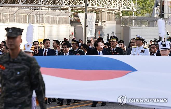 윤석열 대통령, 국군의날 국민과함께 행진 (서울=연합뉴스) 홍해인 기자 = 윤석열 대통령이 1일 서울 광화문 일대에서 열린 국군의날 시가행진에서 대형 태극기를 선두로 국민과 함께 광화문 월대를 향해 행진하며 인사하고 있다. 2024.10.1 hihong@yna.co.kr