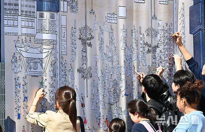 [수원=뉴시스] 김종택 기자 = 수원화성문화제가 열린 4일 경기도 수원시 팔달구 화성행궁 광장에서 '시민도화서 시즌2' 체험 행사에 참여한 시민들이 대형 화성행행도를 재연하는 벽화에 색칠하고 있다. 2024.10.04. jtk@newsis.com