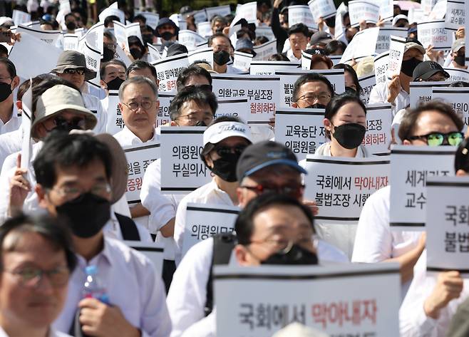 의대교수들이 3일 오후 서울 용산구 대통령실 인근에서 열린 한국의학교육평가원 무력화 저지 결의대회에서 손팻말을 들고 있다. [연합]