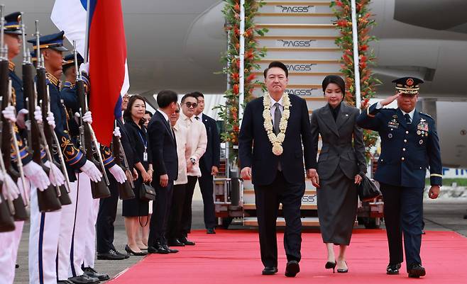 President Yoon Suk Yeol (third from right) and his wife Kim Keon Hee (second from right) walk along a red carpet as they arrived at Ninoy Aquino International Airport in Manila, the Philippines, on Sunday. (Yonhap)