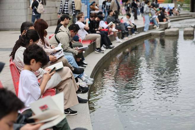 지난 봄 서울 종로구 청계천에 올해 처음 마련된 야외도서관 '책읽는 맑은냇가'를 찾은 시민들이 독서 및 휴식을 즐기고 있다. [사진출처=연합뉴스]