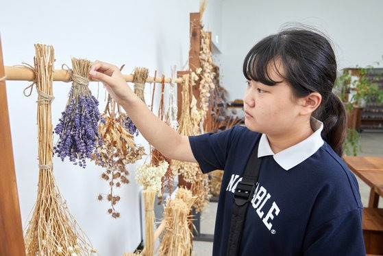 실내식물원에 비치된 드라이플라워를 유심히 바라보는 황민하 학생기자. 아모레퍼시픽은 다양한 꽃 추출물을 화장품 원료로 사용한다.