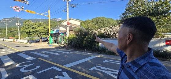 곽동환 이장이 그린리모델링을 통해 지붕에 태양광 패널이 설치된 용담경로당을 가리키고 있다. 버스 정류장 뒤편에 있는 건물이다. 무주=김준희 기자