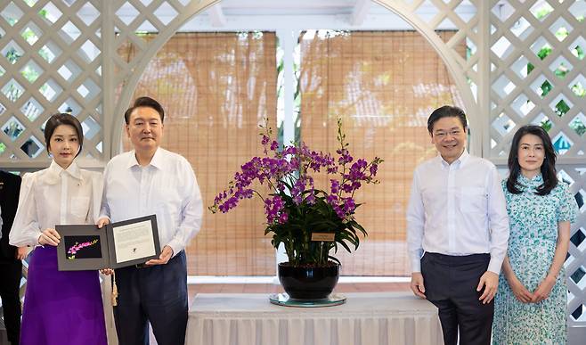 윤석열 대통령과 김건희 여사가 8일(현지 시각) 싱가포르 국립식물원 내 난초정원에서 열린 '난초 명명식'에서 '윤석열·김건희 난' 증명서를 받은 뒤 로렌스 웡 싱가포르 총리 부부와 함께 기념촬영을 하고 있다. /연합뉴스