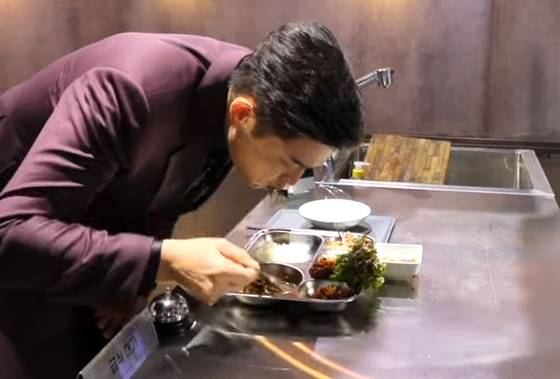 Judge Anh Sung-jae tastes food made by "Master of School Meals," or chef Lee Mi-yeong on round one in Netflix Korea's "Culinary Class Wars" [SCREEN CAPTURE]