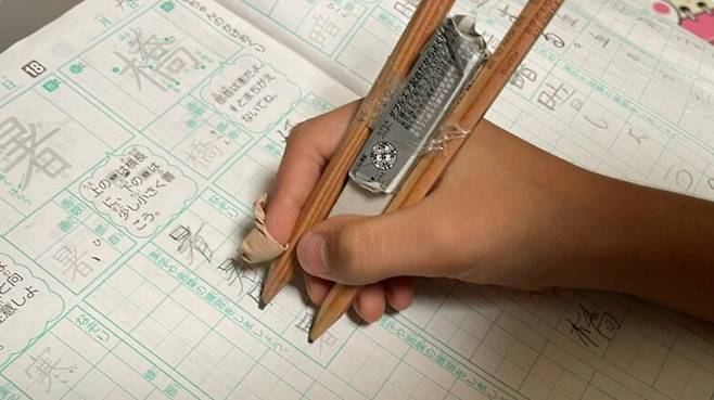 일본의 한 어린이가 한자 쓰기 숙제를 싫어한 나머지 숙제 양을 절반으로 줄일 수 있는 발명품을 만들어 화제다. 연필 2개를 서로 이어 붙인 이 발명품은 한 번에 위 아래 행간을 채울 수 있다. [FNN 갈무리]