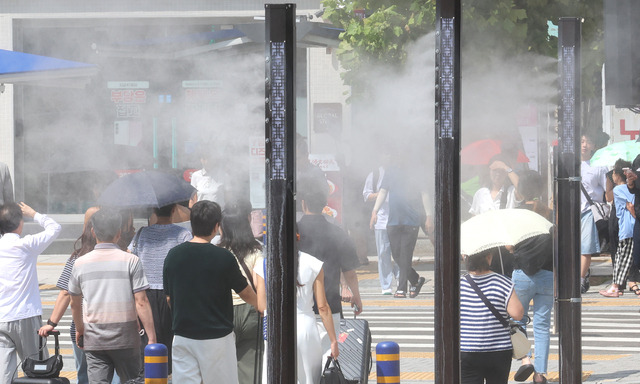 추석 연휴를 하루 앞둔 지난달 13일 부산에 폭염경보가 발효된 가운데 부산역 앞 횡단보도를 지나는 귀성객 등 시민들 사이로 쿨링포그가 가동되고 있다. 연합뉴스