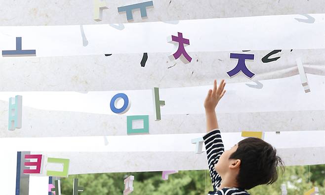 577돌 한글날인 지난 2023년 10월 9일 서울 용산구 국립 한글박물관에 마련된 통로에서 한 아이가 매달린 한글 전시물을 잡으려 하고 있다. 연합뉴스