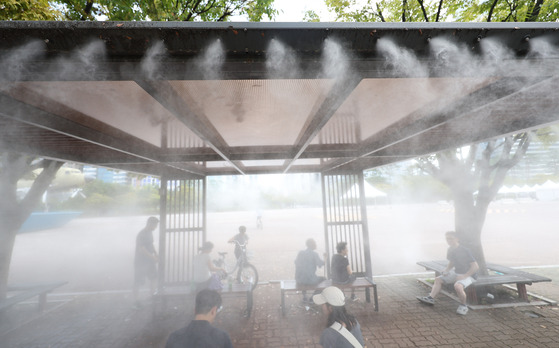 People escape the summer heat under a shade in Yeouido Park in western Seoul on Sept. 18. [YONHAP]