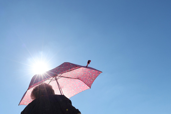 A person walks with a parasol to block the extreme heat in downtown Seoul on Sept. 29. [YONHAP]