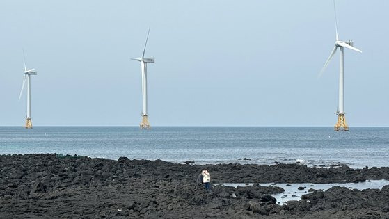 지난 3월 제주도 한경면 해안에서 관광객들이 탐라해상풍력발전 단지의 풍력 발전기를 배경으로 사진을 찍고 있다. 연합뉴스