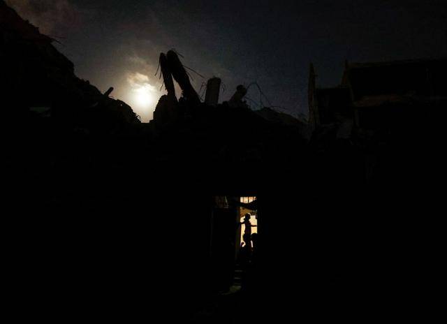 이스라엘과 하마스의 충돌이 이어지고 있는 가운데 15일 정전으로 어둠 속에 갇힌 가자지구 남부 칸 유니스의 부서진 건물더미에서 한 주민이 불을 밝힌 채 생활을 이어가고 있다. 칸 유니스=로이터 연합뉴스