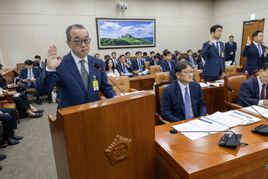 정인섭 한화오션 거제사업장 사장이 15일 오후 서울 여의도 국회에서 열린 환경노동위원회의 경제사회노동위원회, 중앙노동위원회, 최저임금위원회 등에 대한 국정감사에서 선서하고 있다. 정 사장 뒤로 뉴진스 멤버 하니가 참고인 자격으로 앉아 있다. 뉴시스