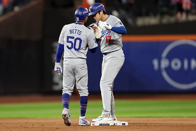 LA 다저스 무키 베츠가 17일(한국시각) 시티필드에서 열린 뉴욕 메츠와 NLCS 3차전에서 3회초 볼넷으로 걸어나간 뒤 먼저 출루한 오타니 쇼헤이와 이야기를 나누고 있다. AFP연합뉴스