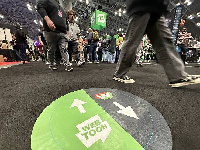 코믹콘 전시장 바닥의 네이버웹툰 부스 안내표시 (뉴욕=연합뉴스) 이지헌 특파원 = 17일(현지시간) 미국 뉴욕에서 개막한 '뉴욕 코믹콘(NYCC) 2024' 행사장 바닥의 네이버웹툰 부스 안내표시.2024.10.17 pan@yna.co.kr