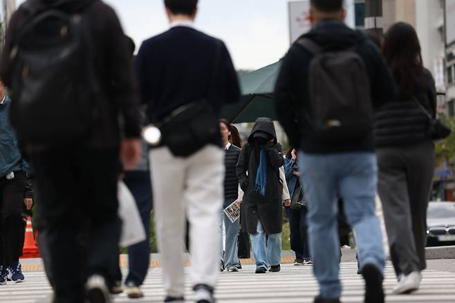 Pedestrians wearing coats cross the street at Gwanghwamun Square in the center of Seoul, Monday. (Yonhap)