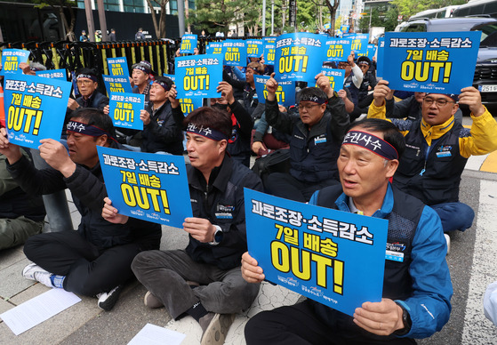 Members of the Korean Public Service and Transport Workers' Union (KPTU) shout slogans and carry signs outside of CJ Logistics' headquarters in Jongno District, central Seoul, on Monday. [YONHAP]