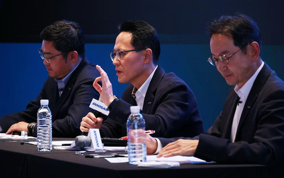 Doosan Enerbilty Chief Financial Officer Park Sang-hyun, center, speaks during a press conference in central Seoul on Monday, with Doosan Robotics CEO Ryu Jung-hoon, left, and Doosan Bobcat CEO and Vice Chairman Scott Park. [YONHAP]