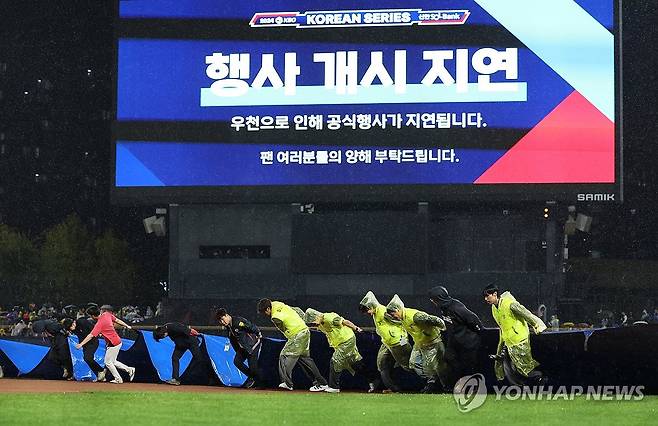 다시 방수포 (광주=연합뉴스) 김도훈 기자 = 21일 2024 신한 SOL뱅크 KBO 포스트시즌 한국시리즈 1차전 삼성 라이온즈와 KIA 타이거즈의 경기가 예정된 광주 기아챔피언스필드에서 경기장 관계자들이 비가 다시 거세지자 철거했던 방수포를 다시 설치하고 있다. 2024.10.21 superdoo82@yna.co.kr