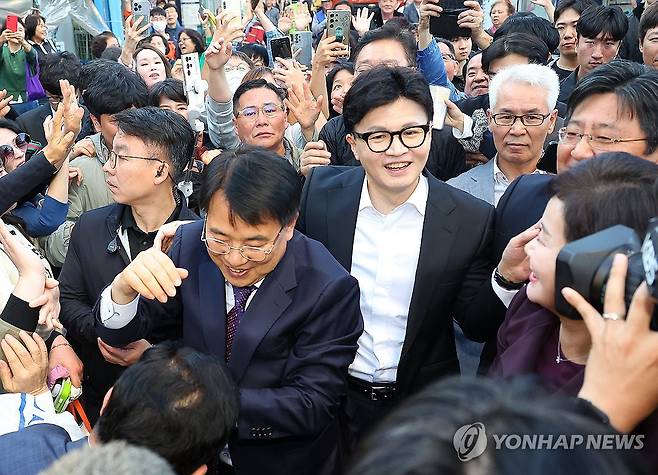 보궐선거 승리 부산 금정구 찾은 한동훈 (부산=연합뉴스) 손형주 기자 = 국민의힘 한동훈 대표가23일 오후 부산 금정구 서동미로시장을 찾아 10·16 재보궐선거에서 당선된 윤일현 금정구청장과 함께 지지자들에게 인사하고 있다. 2024.10.23 handbrother@yna.co.kr