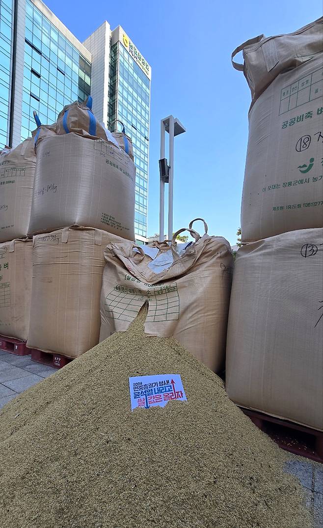 전국농민회총연맹(이하 ‘전농’)과 전국쌀생산자협회가 24일 오후 서울 농협중앙회 본관 앞에서 기자회견을 열고 나락값 7만원 공약 이행 등 즉각적인 쌀값 안정화 대책 마련을 촉구하는 가운데 나락포대에 항의 피켓이 놓여있다.