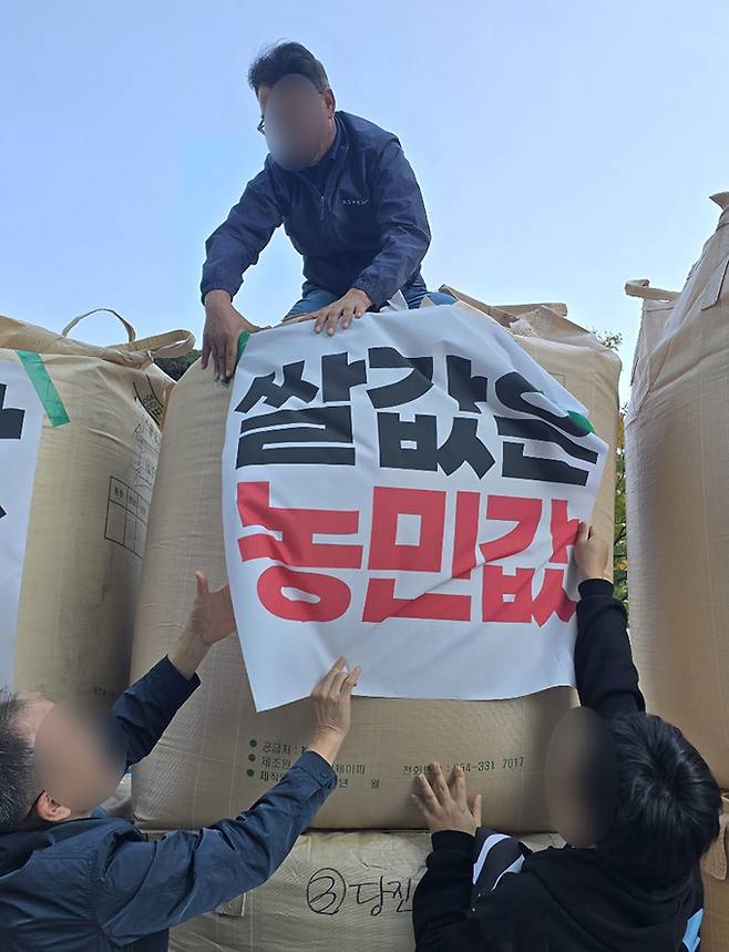 전국농민회총연맹(이하 ‘전농’)과 전국쌀생산자협회가 24일 오후 서울 농협중앙회 본관 앞에서 기자회견을 열고 나락값 7만원 공약 이행 등 즉각적인 쌀값 안정화 대책 마련을 촉구하는 가운데 관계자들이 나락포대에 항의 문구를 붙이고 있다.