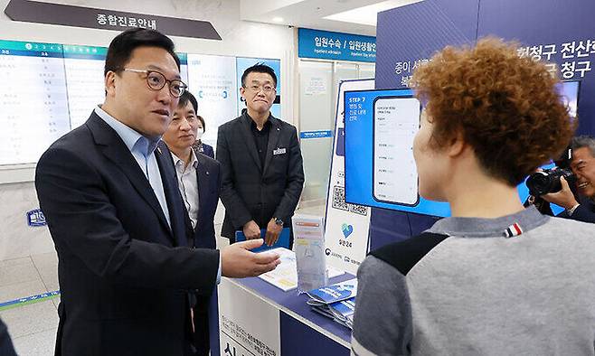 김병환 금융위원장(왼쪽)이 25일 오전 서울 여의도 성모병원에 설치된 실손청구 전산화 홍보 부스에 방문해 현장 안내직원의 설명을 듣고 있다.&nbsp; &nbsp; 금융위원회 제공