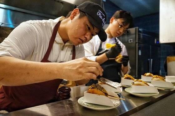 오준탁 셰프가 핫도그 모양으로 변형한 츠쿠네 위에 트러플로 마무리하고 있다. 사진 김성현