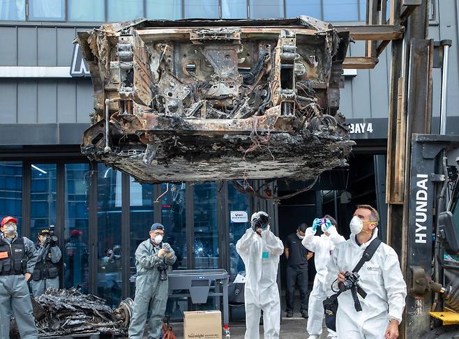 A Mercedes-Benz Germany employee (right) examines the burned-out Mercedes-Benz EQE 350+ electric vehicle during a second joint forensic investigation by the National Police and the National Forensic Service at a repair shop in Incheon on Aug. 8. (Newsis)