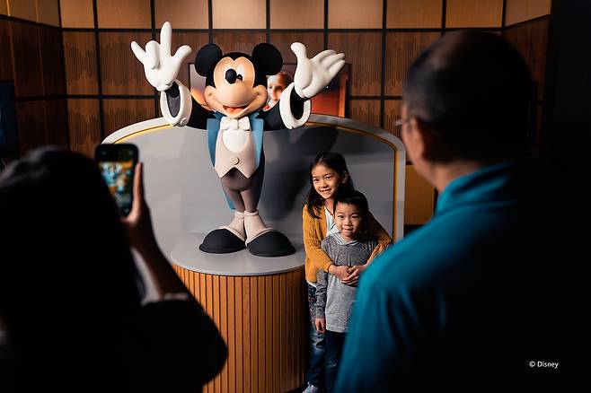 Visitors pose with a Mickey Mouse statue at “Disney100: The Exhibition,″ now on view at the K Museum of Contemporary Art in southern Seoul. [EXHIBITION HUB ASIA]