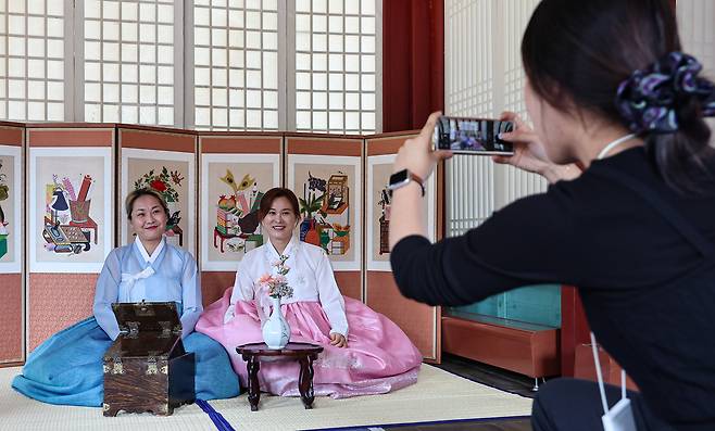 Tourists take pictures wearing Korean traditional dress hanbok at the Changgyeong Palace on Oct. 16, central Seoul. [NEWS1]