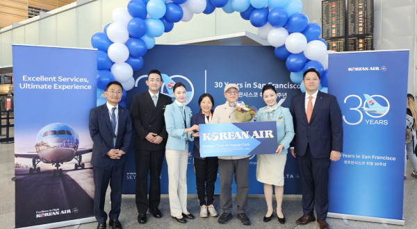 The 30th passenger for Korean Air flight KE024 to Incheon receives a round-trip ticket and poses with airline representatives. (Korean Air Lines)