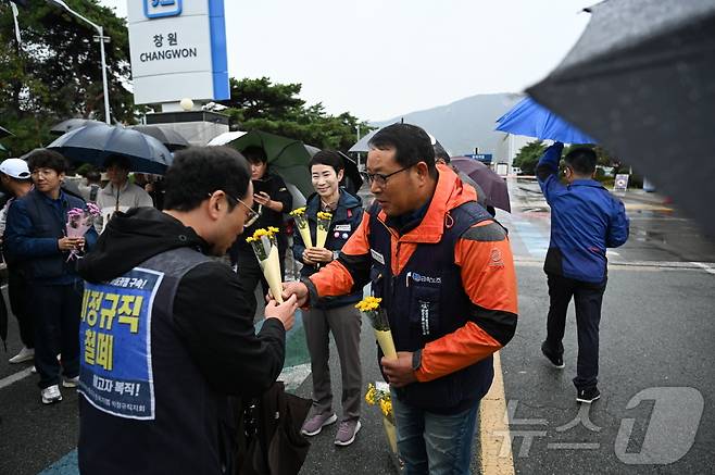 1일 오전 7시 30분쯤 한국지엠 창원공장 앞에서 금속노조 경남지부가 이날 첫 출근에 나선 한국지엠 비정규직 노조 조합원들에게 꽃송이를 전하고 있다.(금속노조 경남지부)