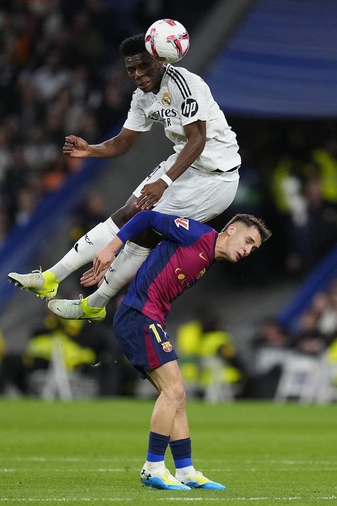 Real Madrid's Aurelien Tchouameni jumps for a header on top of Barcelona's Marc Casado during a Spanish La Liga soccer match between Real Madrid and Barcelona at the Santiago Bernabeu stadium in Madrid, Spain, Saturday, Oct. 26, 2024. (AP Photo/Manu Fernandez) <저작권자(c) 연합뉴스, 무단 전재-재배포, AI 학습 및 활용 금지>